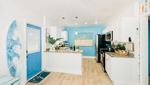Una cocina con armarios blancos, pared de acento azul, refrigerador de acero inoxidable y microondas.