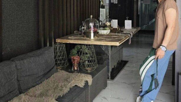 Ein modernes Interieur mit einer Couch, einem Tisch mit Dekoration und einer stehenden Person.
