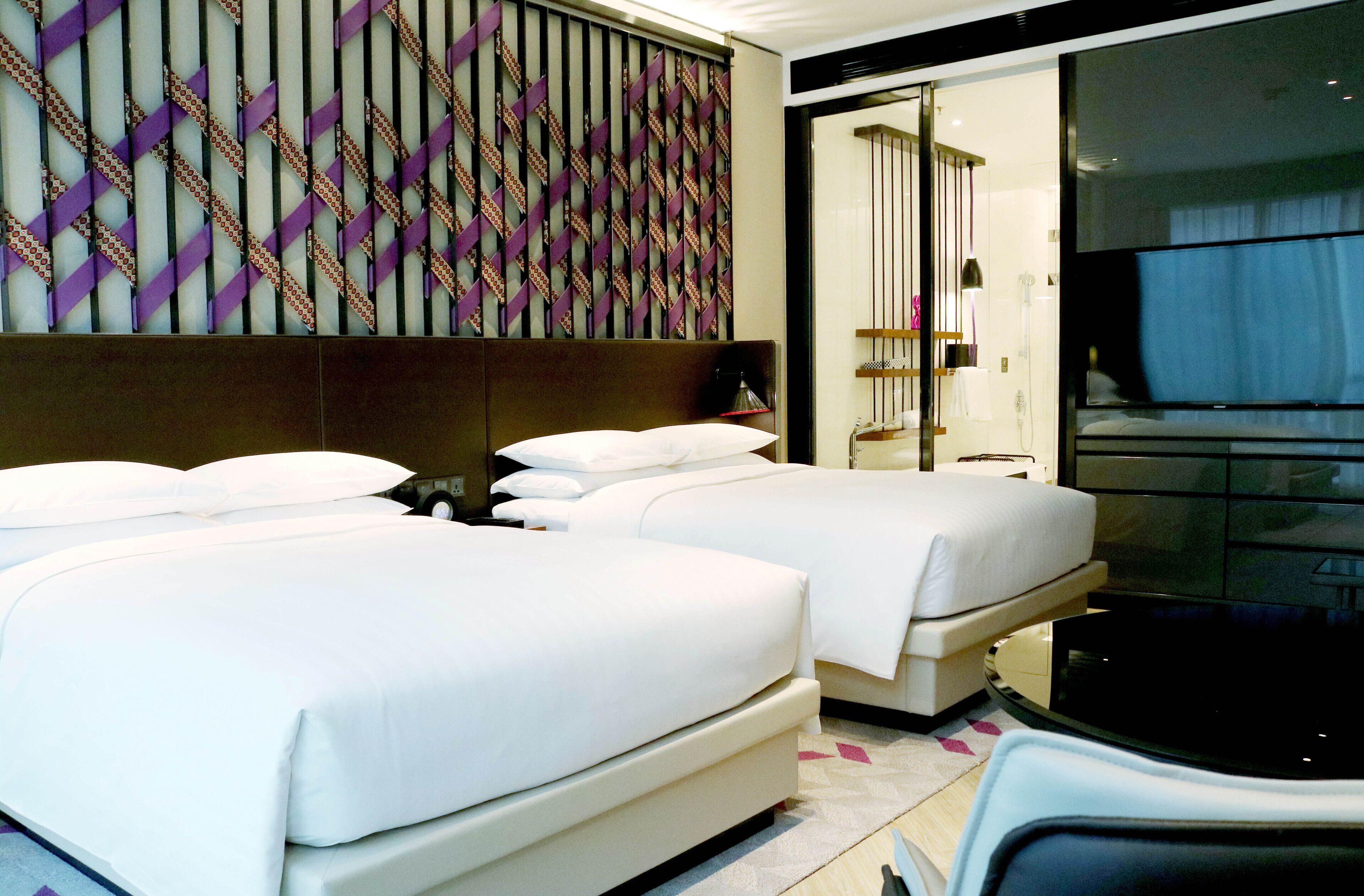Habitación de hotel con dos camas, un espejo grande y zona de ducha.