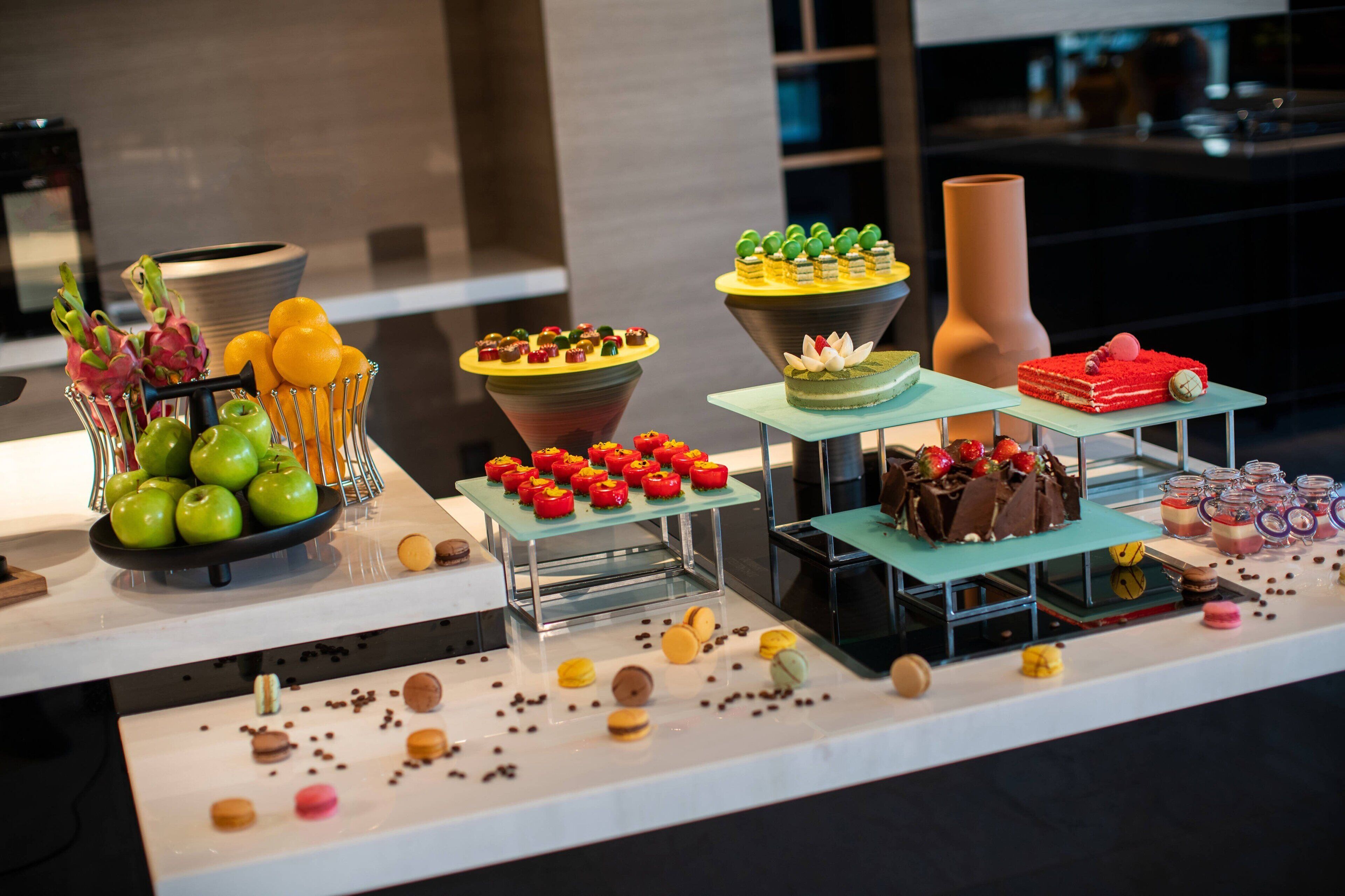 Uma mesa com diversos doces, bolos e frutas.