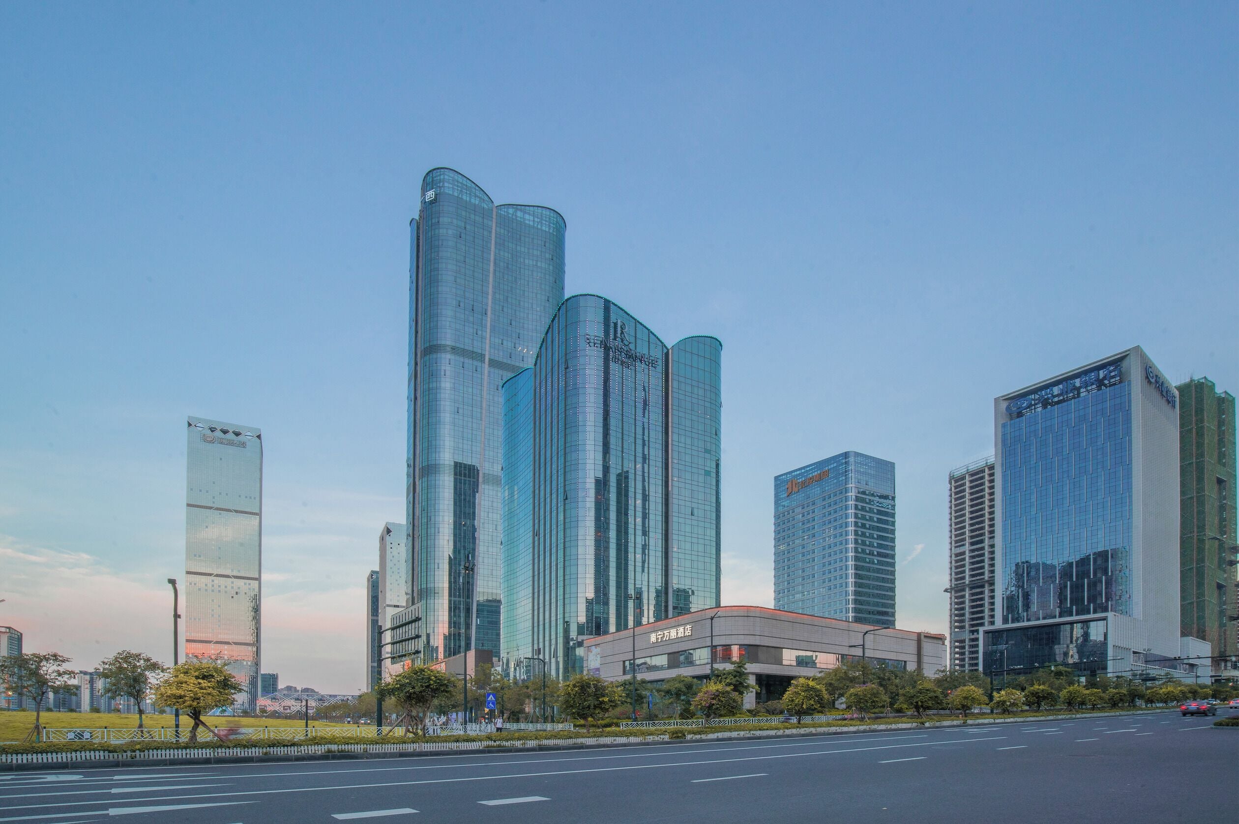 Un paisaje urbano moderno con rascacielos, una avenida amplia y un cielo despejado.