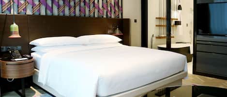 A modern hotel room with a large bed, bedside tables, a desk, and a TV.