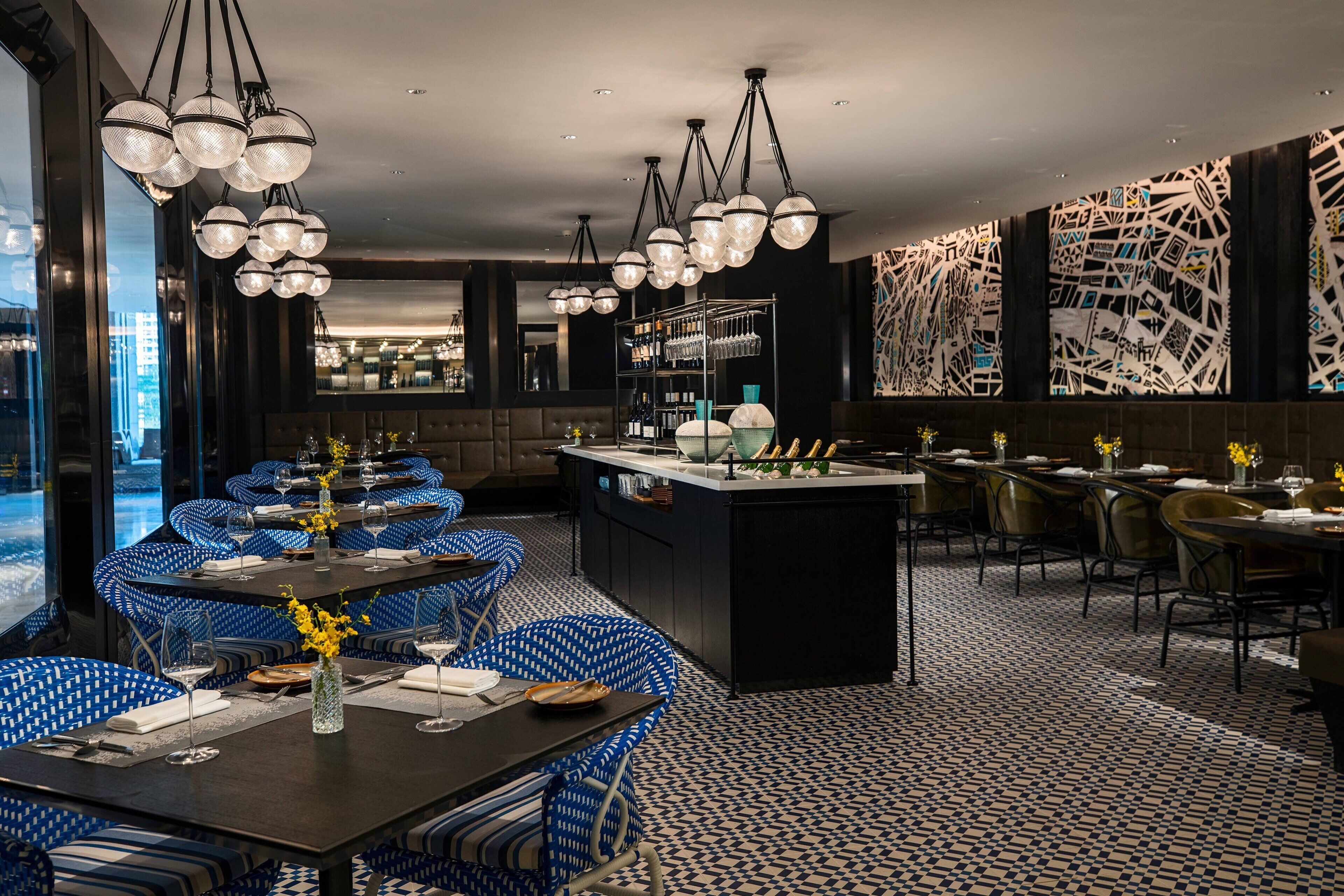 Un restaurante con mesas redondas, sillas estampadas azules y lámparas esféricas colgantes.