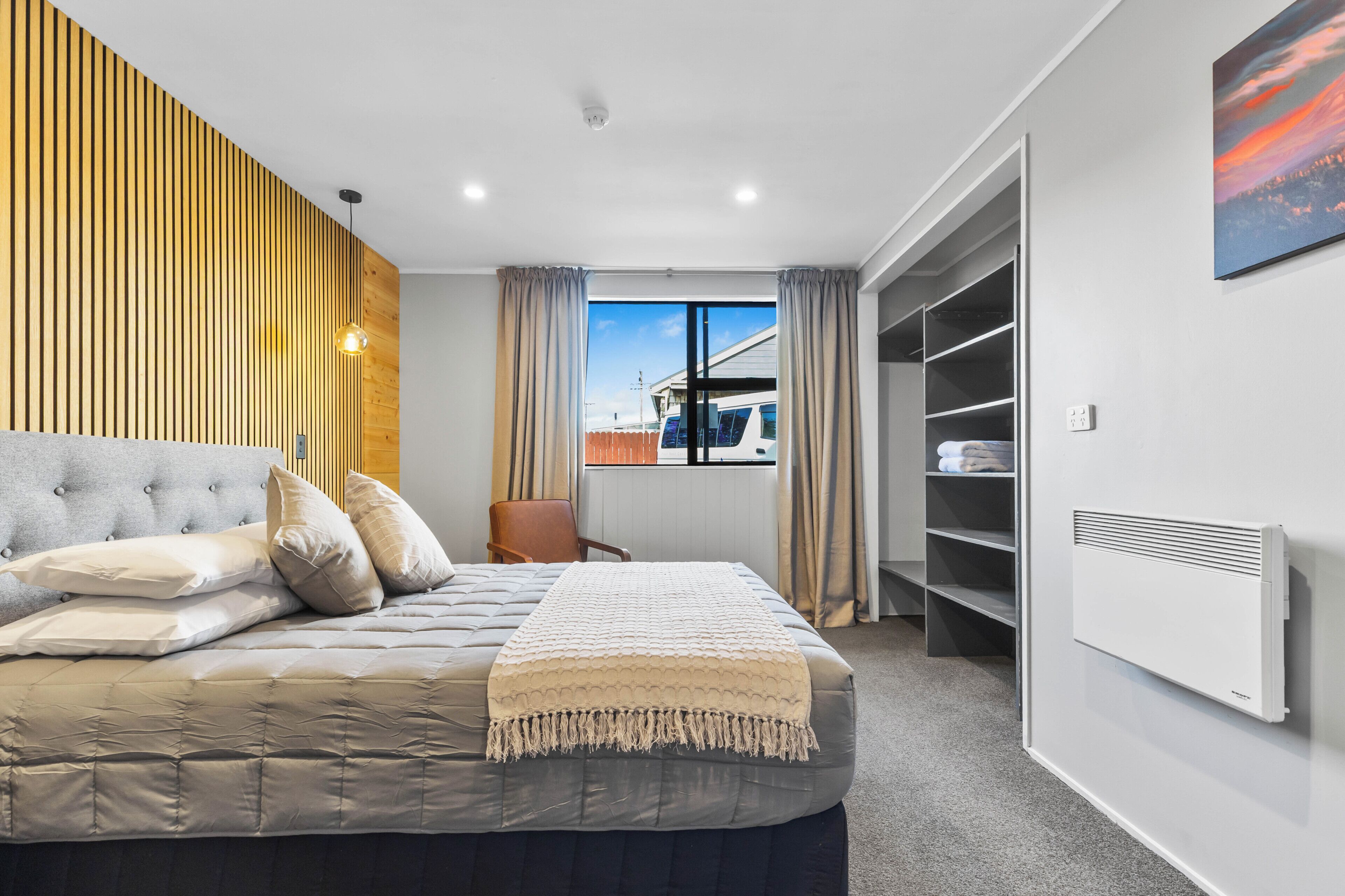 A modern bedroom with a bed, a view of the city, and a built-in wardrobe.