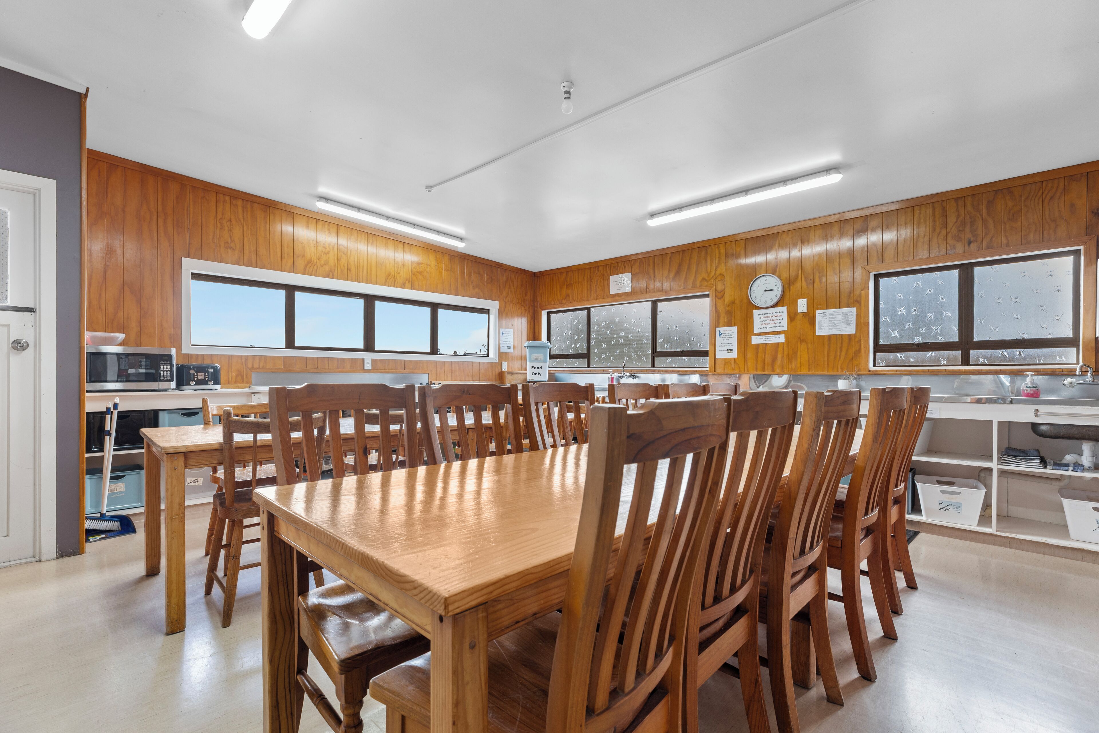 A spacious kitchen with wooden cabinetry, a large dining table, and multiple chairs.