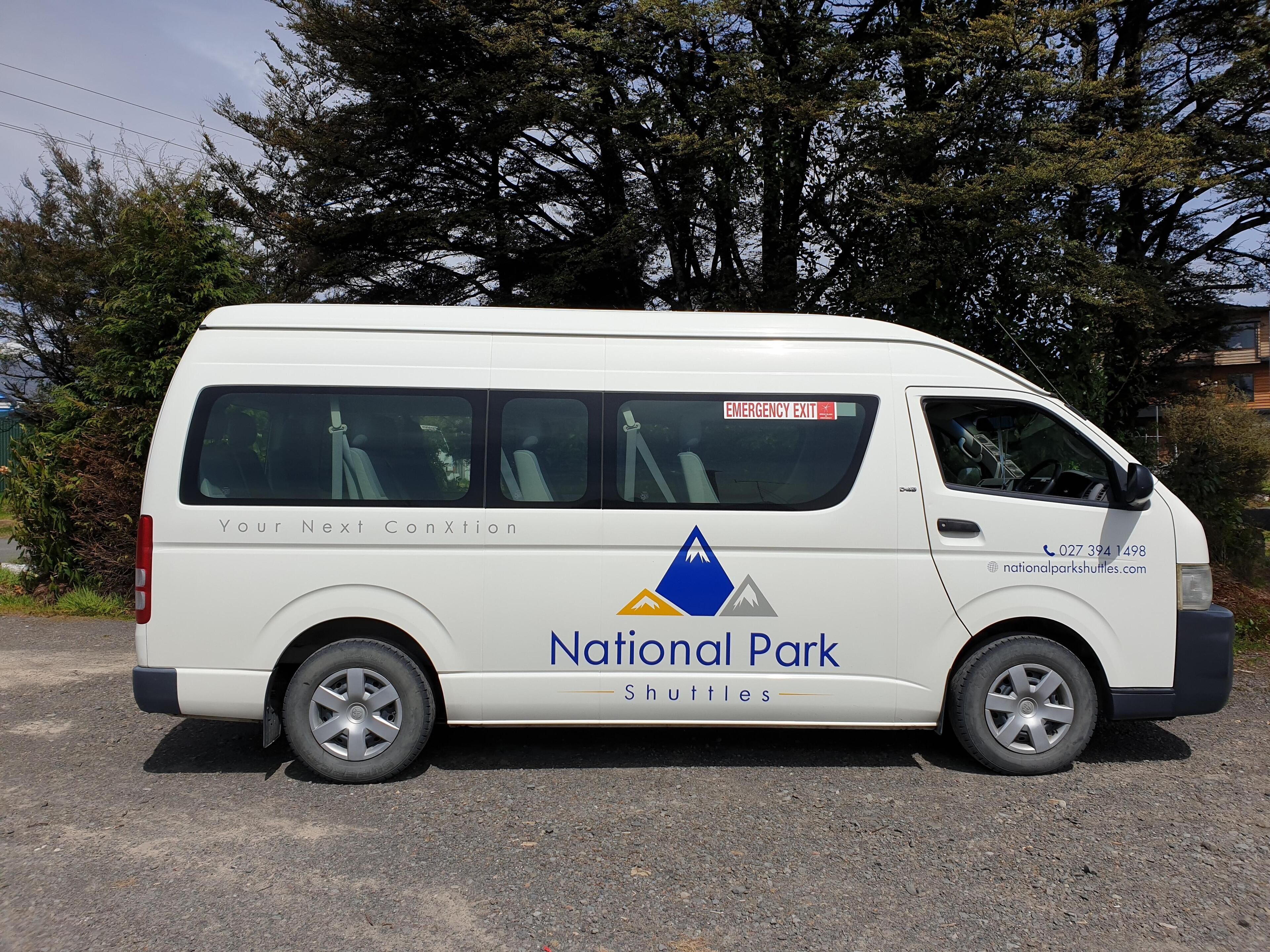 Un fourgon blanc arborant le logo « Navettes des parcs nationaux » et portant un panneau indiquant la sortie de secours.