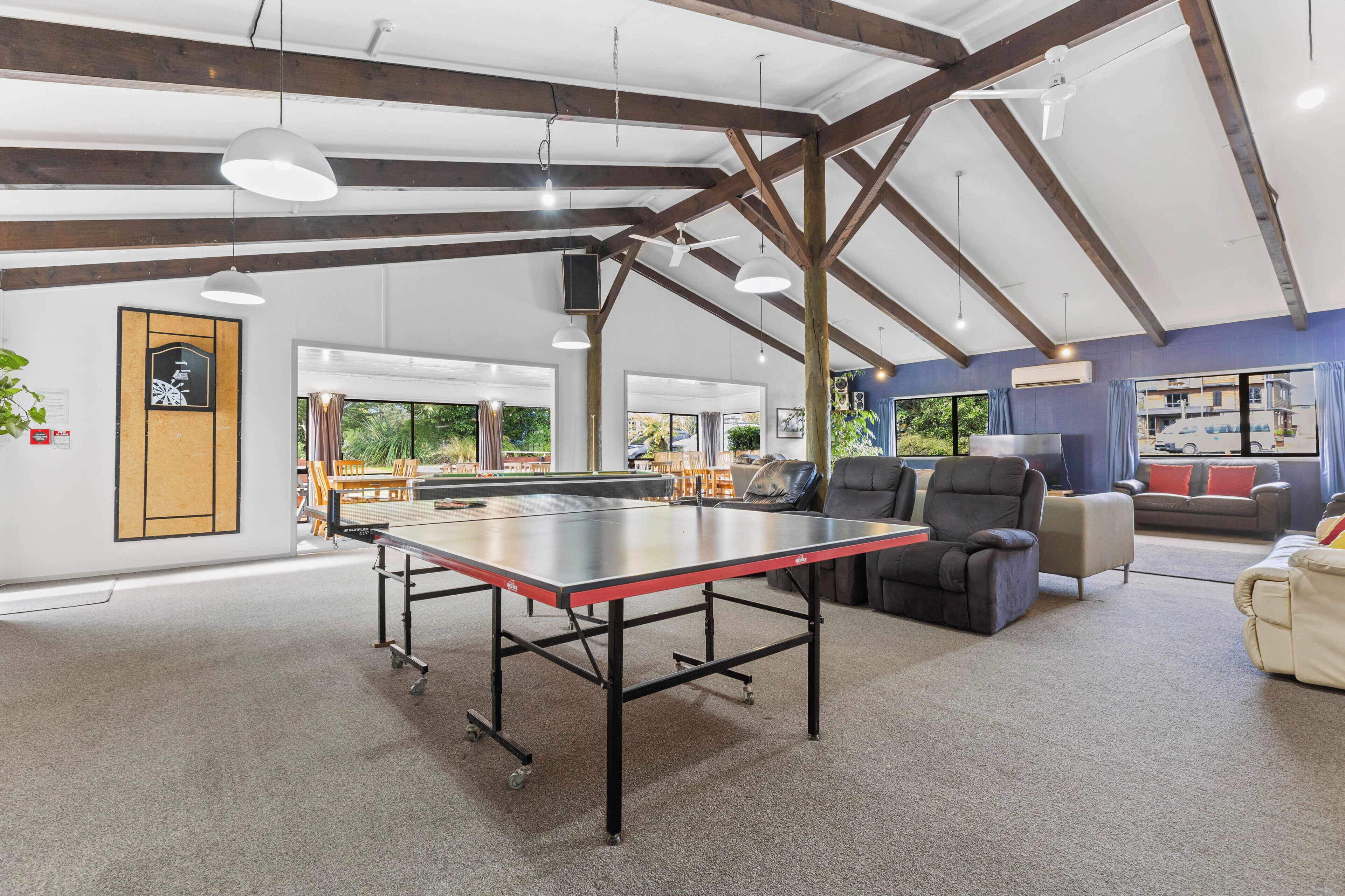 A spacious room with a ping pong table, seating area, and large windows.