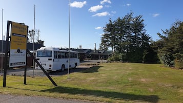 Un autobús estacionado en una parada de transporte del parque nacional, con un cartel que indica Manowhen Lodge.