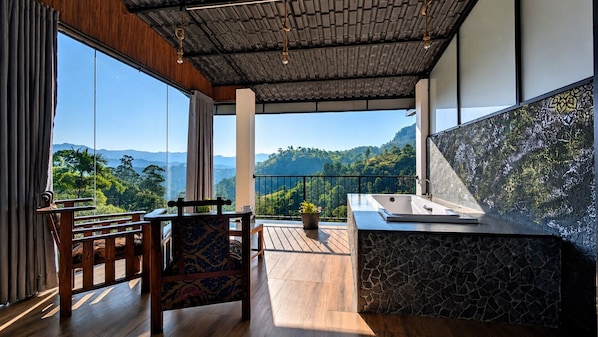 Ein Balkon mit Blick auf Berge, ein Holztisch mit Stühlen und eine Steinarbeitsplatte mit Spüle.