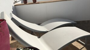 A sun lounger with a metal frame and a cushion, positioned on a tiled patio with a potted plant nearby. - Town house Sant Llorenc, east coast Mallorca, 15 minutes to the beach (Sant Llorenc)
