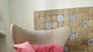 A beige armchair with a pink fluffy pillow and a beige furry rug on the floor. - Town house Sant Llorenc, east coast Mallorca, 15 minutes to the beach (Sant Llorenc)