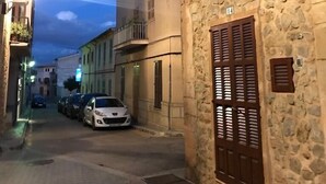 A narrow street with stone buildings, parked cars, and a clear sky. - Town house Sant Llorenc, east coast Mallorca, 15 minutes to the beach (Sant Llorenc)