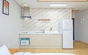 Cocina compacta con microondas, fregadero y refrigerador.