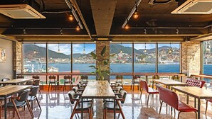 Un restaurant doté de grandes fenêtres donnant sur une ville côtière.