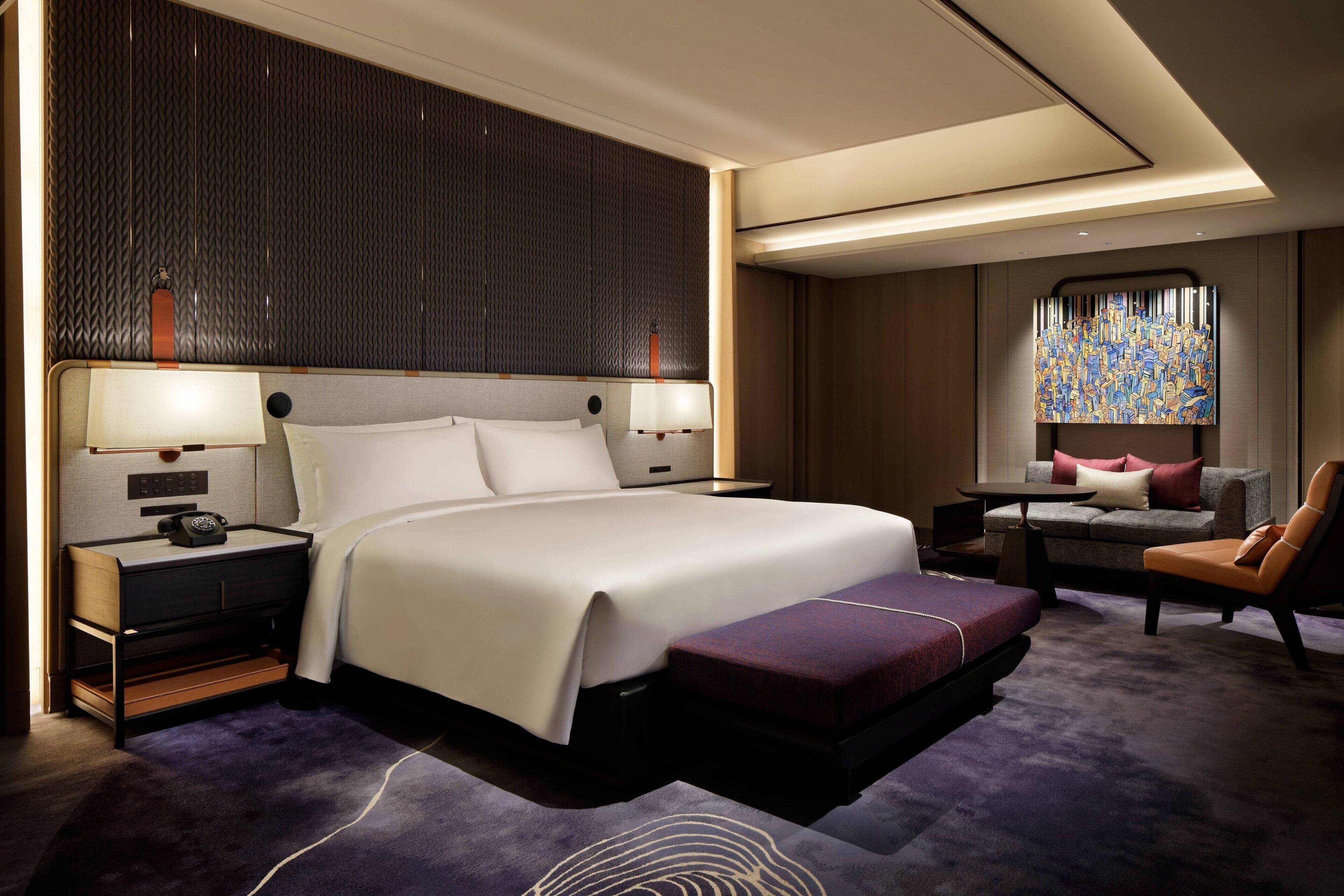 Ein modernes Hotelzimmer mit einem großen Bett, Nachttischen, einem Schreibtisch und einer Sitzecke.