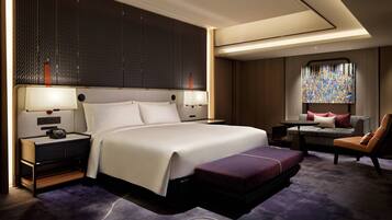 Ein modernes Hotelzimmer mit einem großen Bett, Nachttischen, einem Schreibtisch und einer Sitzecke.