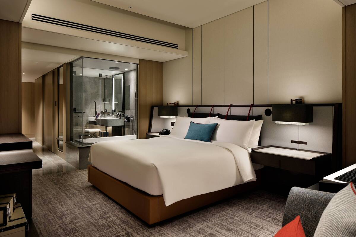 A modern hotel room with a large bed, bedside tables, a desk, and a mirror.