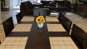A dining area with a dark wooden table, woven placemats, and a vase of sunflowers. - Charming private pool home 3br/ 2 bath (West Palm Beach)
