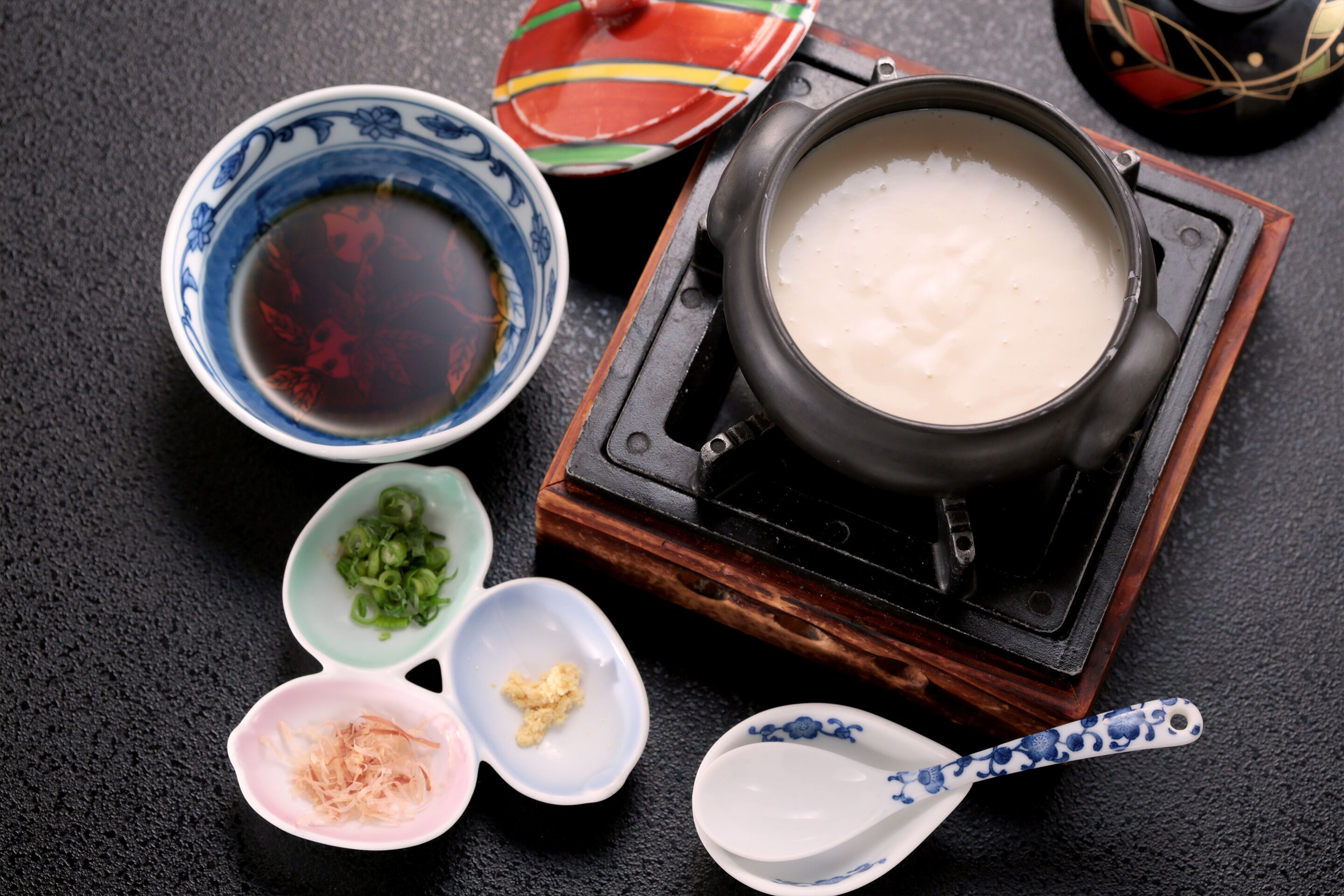 Uma preparação tradicional japonesa de panela, com uma panela de arroz, uma tigela de molho de soja e pequenas tigelas com cebolinha e gengibre.