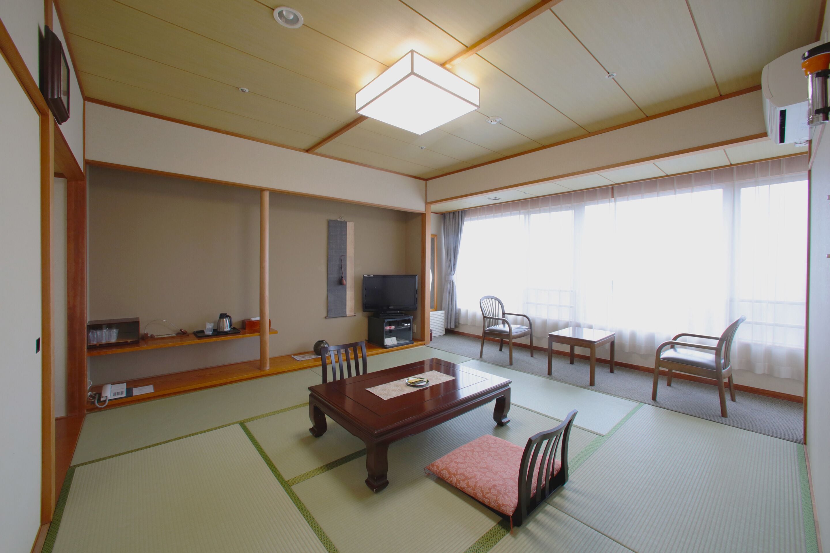 A traditional Japanese-style living room with tatami flooring, a low wooden table, and a television.