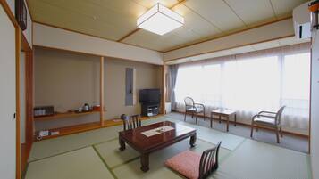 A traditional Japanese-style living room with tatami flooring, a low wooden table, and a television.