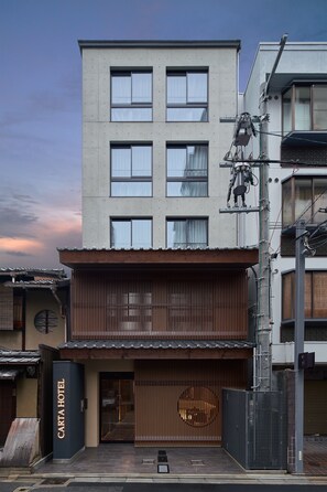 Ein modernes Hotel mit flacher Fassade, großen Fenstern und einem traditionellen Eingang mit einem Holztor.