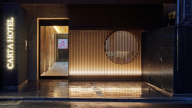 A hotel entrance with vertical wooden slats and a circular design element. - Carta Hotel KyotoBettei (Kyoto)