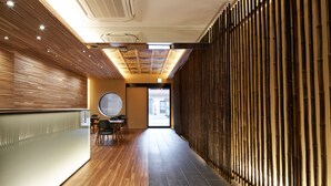 A modern interior with wooden paneling, a reception desk, and a seating area with tables and chairs. - Carta Hotel KyotoBettei (Kyoto)