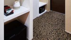 A hotel room with white shelving units, a black suitcase, and a patterned carpet. - Carta Hotel KyotoBettei (Kyoto)