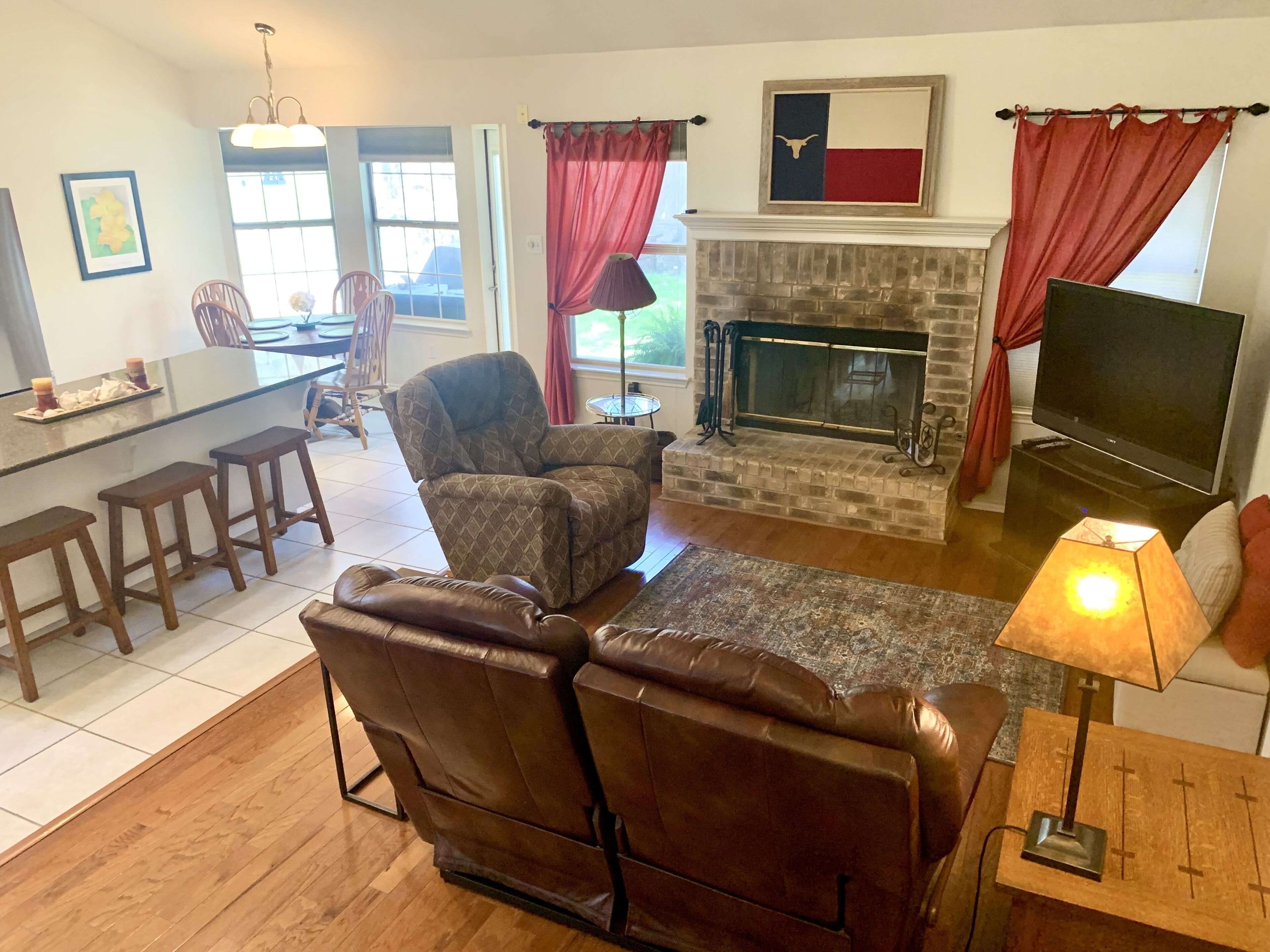 A living room with a fireplace, a TV, and a dining area with a bar.