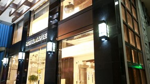 Ein Hotel mit Glastür, einem sichtbaren Aufzug und einem Schild mit der Aufschrift "HOTEL MAPLE".