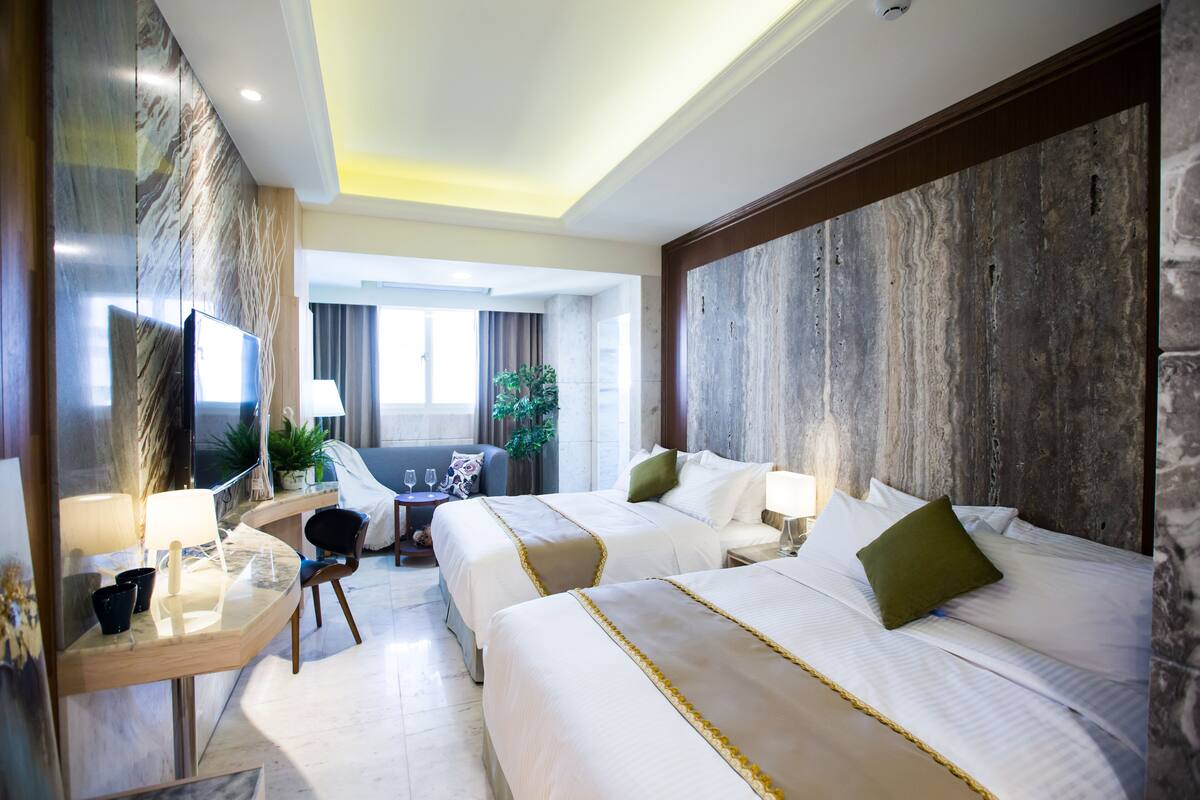 Una habitación de hotel con dos camas, un escritorio, un televisor y vistas al exterior.