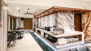 Eine moderne Hotelhalle mit einer Marmor-Rezeption, einer Sitzecke und einer Kaffeestation.