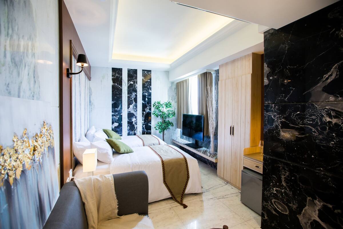 Una habitación de hotel moderna con una cama grande, televisión, escritorio y zona de estar.