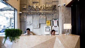 Ein Empfangsbereich mit Steinwand im Hintergrund, einem Schild für das Hotel Nanjing Tainan Boulevard und einer Überwachungskamera.