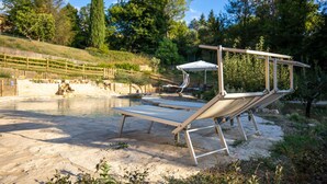 Un espace piscine avec deux chaises longues et un coin salon abrité.