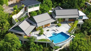 Ein modernes Haus mit Swimmingpool, umgeben von üppigem Grün.