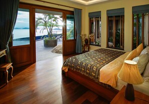A spacious bedroom with a large bed, a bedside lamp, and a view of the ocean through a sliding glass door. - Ocean View Luxury Bed Villa with lovely Infinity Pool, FREE CAR & Free Transfers (Koh Samui)