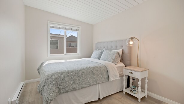 A bedroom with a bed, a nightstand, a lamp, and a window.