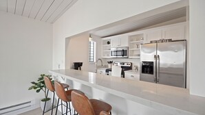 Una cocina moderna con una isla central, electrodomésticos de acero inoxidable y taburetes de bar.