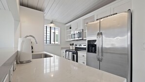 Una cocina moderna con electrodomésticos de acero inoxidable, encimera de mármol y ventana que aporta luz natural.