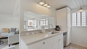 Una cocina moderna con un espejo grande, armarios blancos, un lavamanos y una cafetera.
