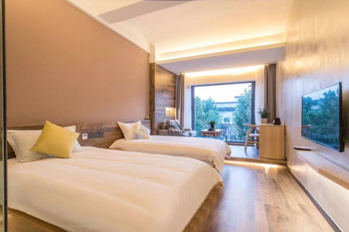 A hotel room with two beds, a TV, and a balcony with a view.