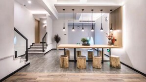 A modern reception area with a wooden reception desk, black pendant lighting, and a staircase on the left. - Suzhou Jianluju Inn (Suzhou)