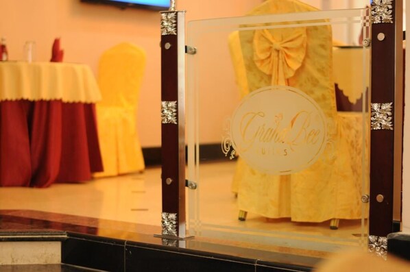 A glass display case with a yellow dress and a logo that reads "Crown Bee."