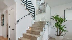 A modern staircase with glass railings and wooden steps, leading to a landing with a potted plant. - Exceptional Hilltop Villa with Panoramic View (SF)