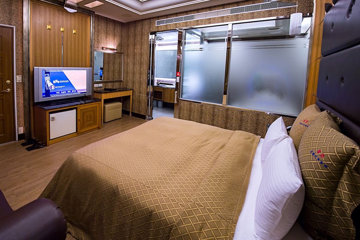 Een hotelkamer met een bed, een televisie, een bureau en een kledingkast.