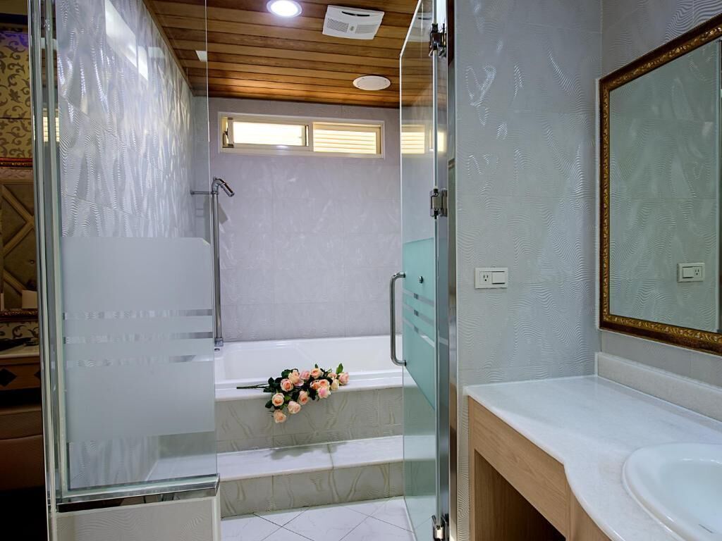 A modern bathroom with a glass shower enclosure, a white bathtub, and a wooden vanity with a mirror.