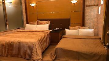 A hotel room with two beds, a wooden headboard, a nightstand, and a mirror.