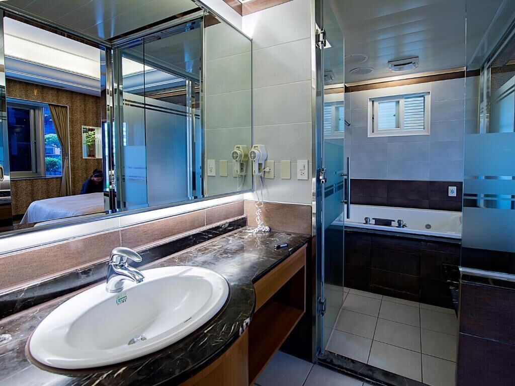 Une salle de bain moderne avec un grand miroir, un lavabo et un espace douche.